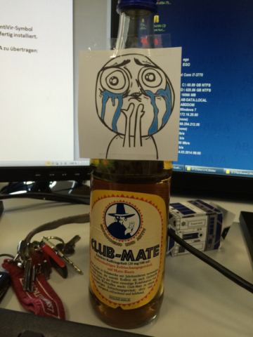Bild einer Flasche Club Mate auf meinem Schreibtisch mit einem weinenden Meme darauf.