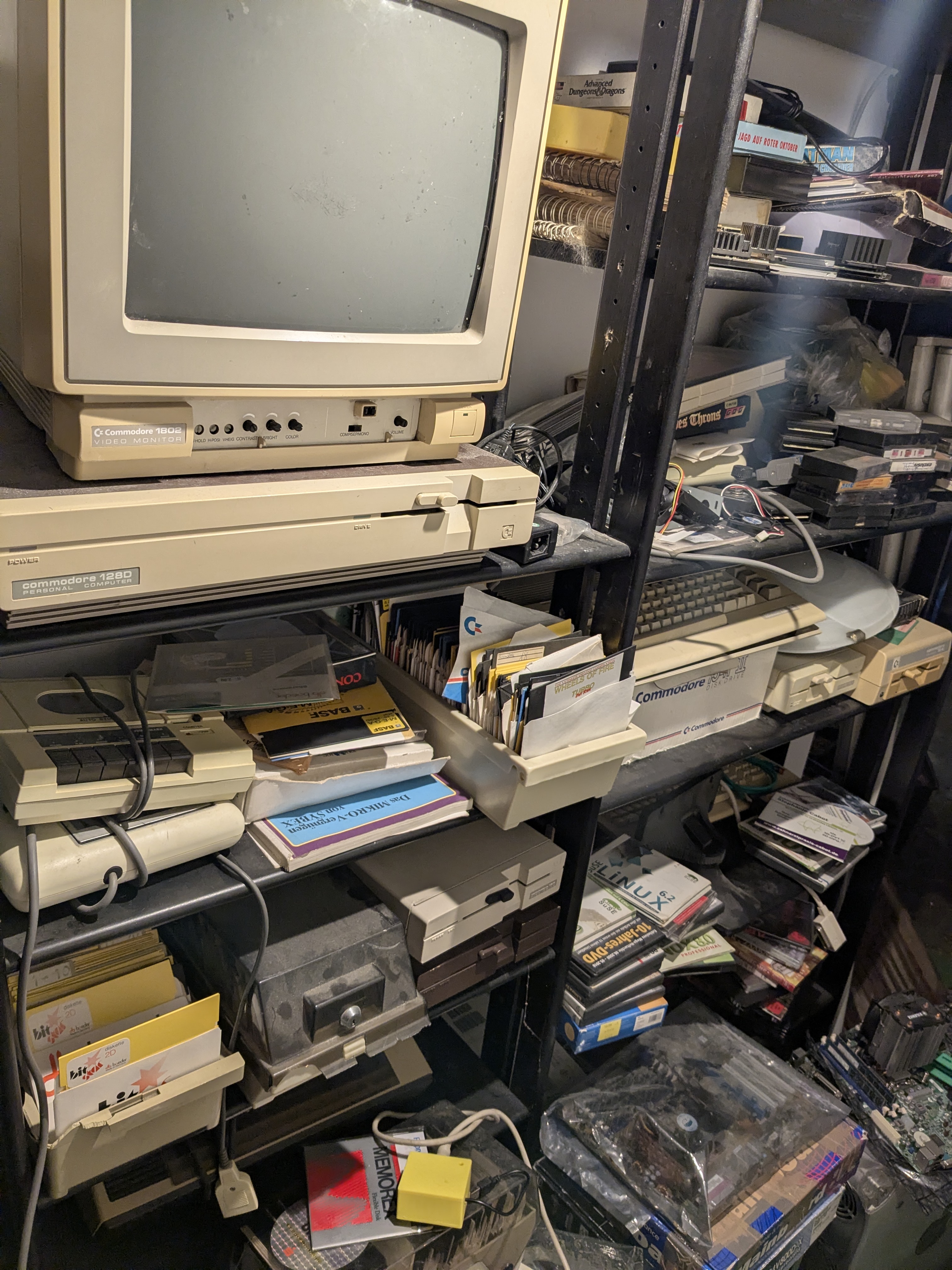 Retro-Computing-Regal mit Commodore-Monitor, 1571 Laufwerk, C128 Tastatur, Diskettenstapeln und dem gelben xum1541-Adapter