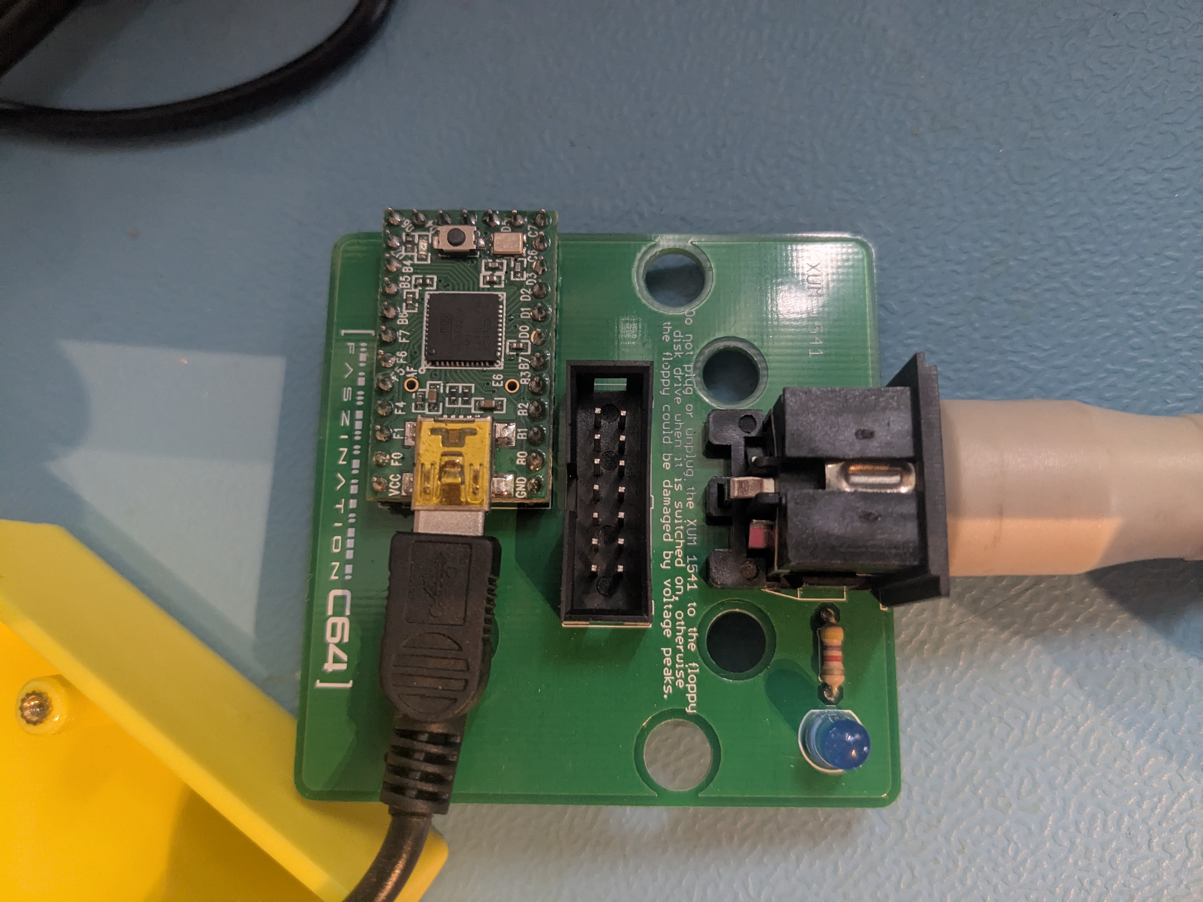 Geöffneter xum1541-Adapter mit Teensy2-Board (ATmega32U4) auf der Platine, USB-Anschluss und IEC-DIN-Buchse