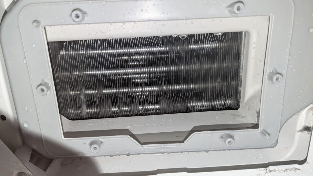 Gereinigter Kondensator mit blanken Aluminiumlamellen und freien Luftkanälen nach dem Absaugen