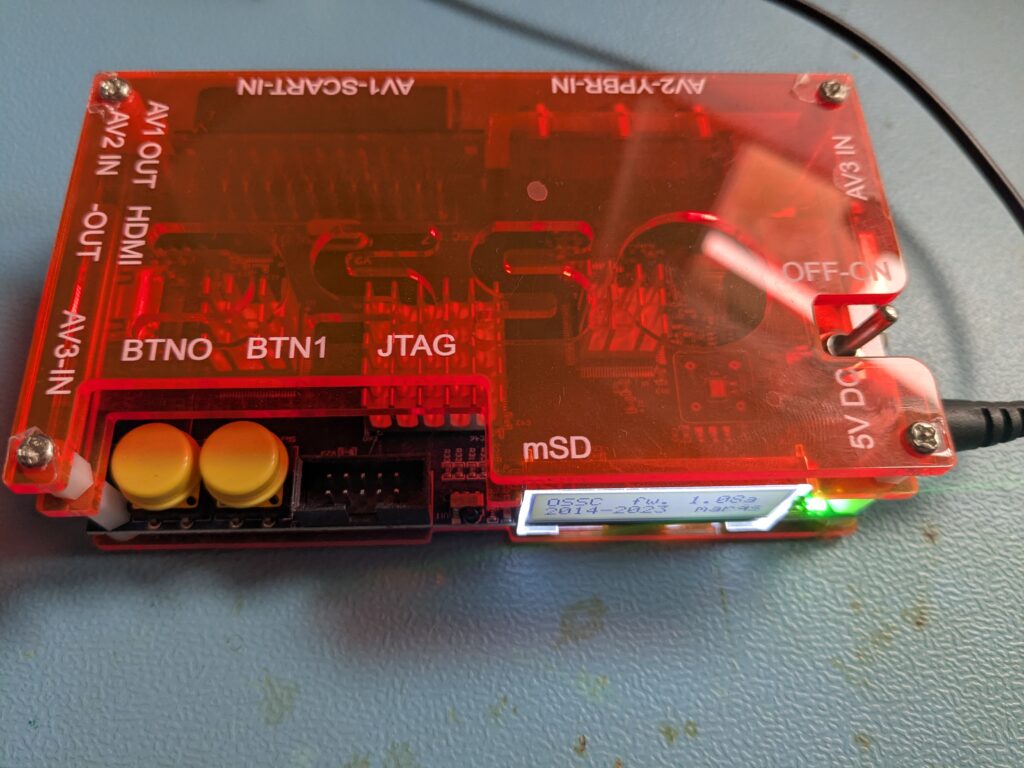Top-Down-Ansicht des Open Source Scan Converter mit allen Anschlussbeschriftungen: AV1 OUT HDMI, AV2 IN, AV1-SCART-IN, AV2-YPBR-IN, AV3 IN, OFF-ON-Schalter, 5V DC, BTN0, BTN1, JTAG-Pins und mSD-Slot
