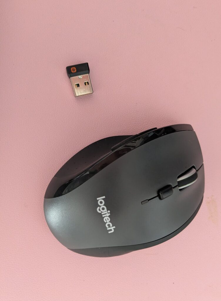 Die Logitech Marathon Mouse M705 und ein Unifying-Empfänger mit orangem Stern auf einer Tischplatte.