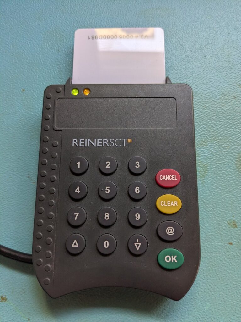 REINER SCT cyberJack pinpad(a) Kartenleser mit Zifferntastatur, LEDs und eingesteckter OpenPGP-Karte.
