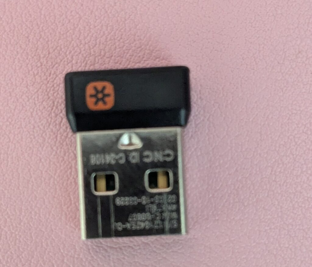 Nahaufnahme eines Logitech-Unifying-Empfängers, der orange Unifying-Stern ist deutlich lesbar.